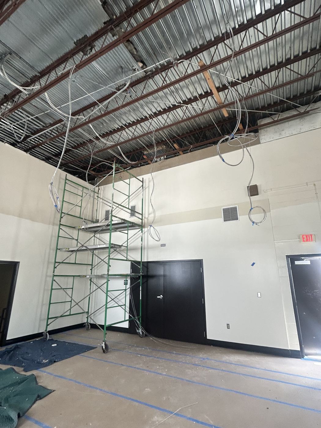 Classroom with ceiling removed to the deck, scaffold in place, floors fully covered in protective paper and tape.