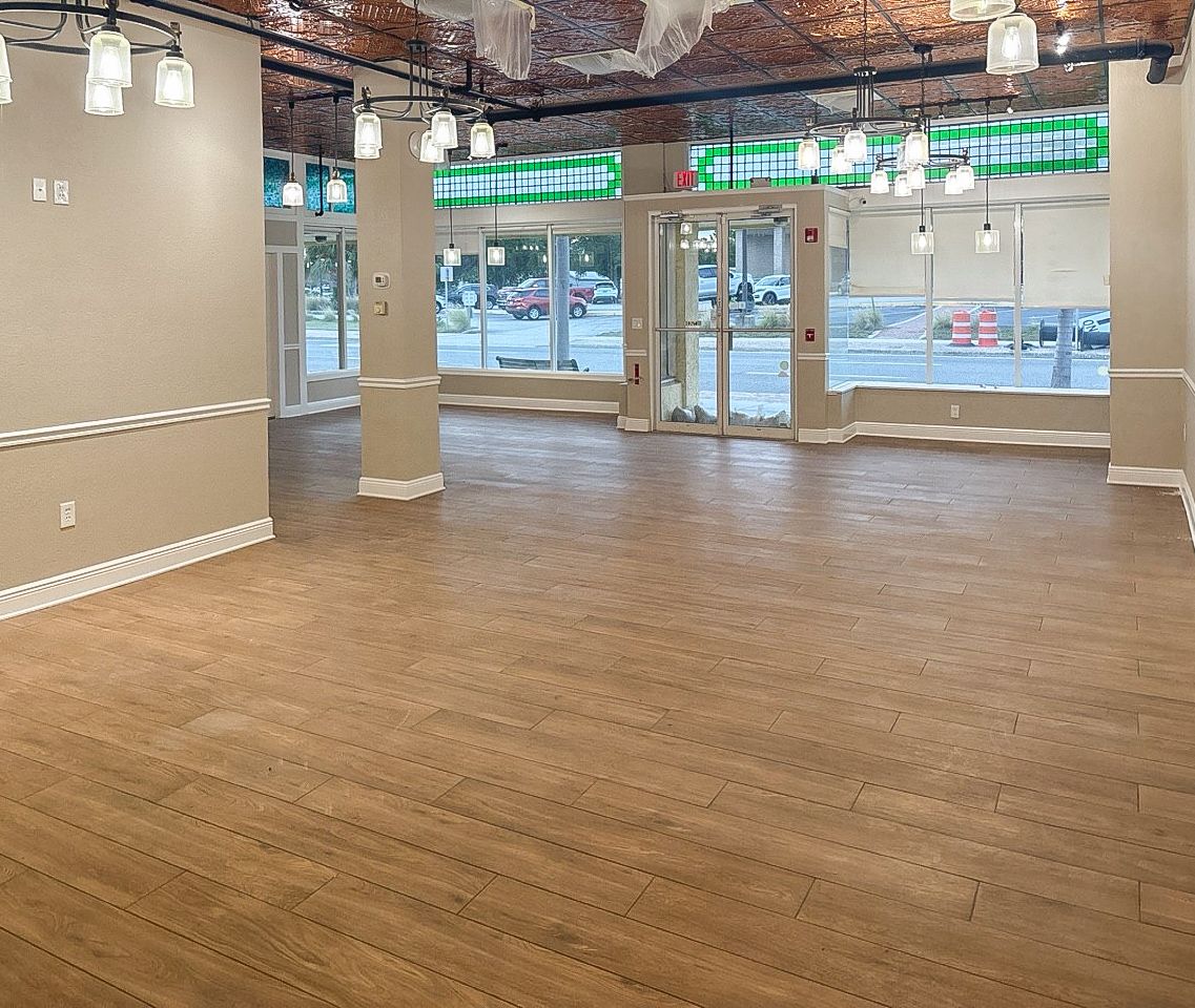 Finished salon storefront with new wood-look tile floors, pendant lighting, pressed-tin ceiling, and stained-glass transoms.